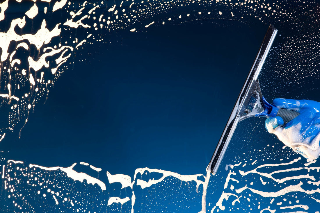 A soapy window with a squeegee cleaning the glass