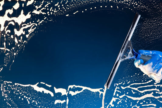 A soapy window with a squeegee cleaning the glass