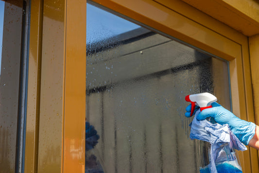 a window cleaners hand holding a spray bottle to clean a window