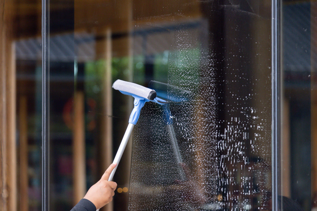 A person is cleaning a window with a water fed pole and squeegee