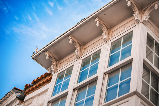 Low angle view of a white vintage bay window reflecting the blue sky
