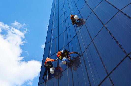 three men cleaning windows on a high rise building
