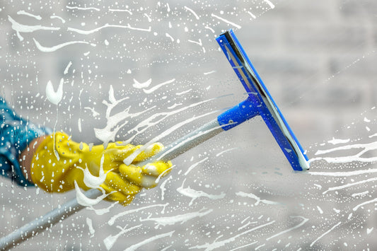 a gloved hand holding the pole of a window squeegee